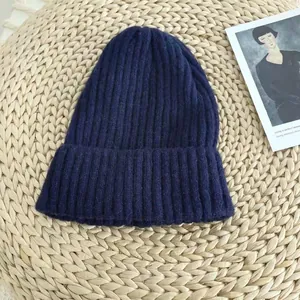 Detailed view of a navy blue ribbed knit beanie hat on a straw textured surface