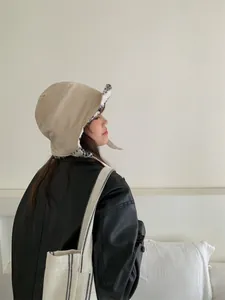 Vue de profil d'un bonnet d'aviateur d'hiver en daim beige avec doublure en fausse fourrure.