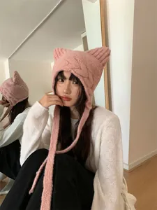 Detailed view of a cute pink knitted cat ear beanie with ear flaps on a model.
