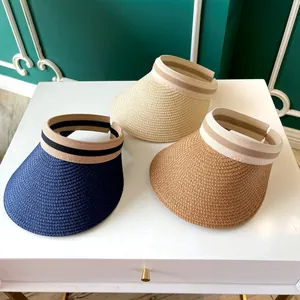 Vue de dessus de trois couleurs de visières en paille sur un piédestal blanc épuré