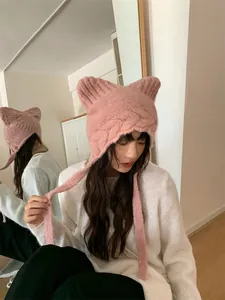 Detail view of pink knitted hat with cute cat ears and long earflaps for winter