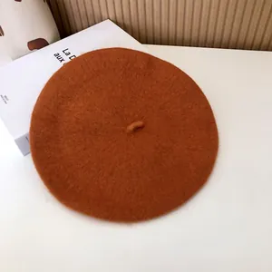Close-up of a vintage orange wool beret showing soft felt texture and classic top tab.