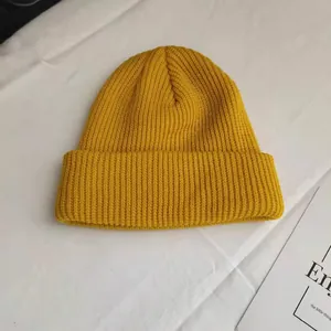Close-up of yellow knitted short beanie with ribbed texture and a stylish folded brim