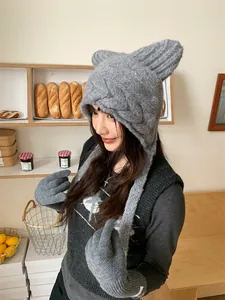 Detail of gray cat ear knitted hat and gloves worn by female model in cafe setting