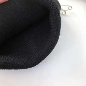 Vista dettagliata del berretto nero a coste con eleganti spille da balia decorative
