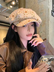 Close-up of a stylish pink floral newsboy cap worn by a model in a trendy indoor setting.