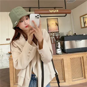 Detailed view of stylish olive green pleated bucket hat for women in a cafe setting