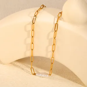 Vue détaillée d'un collier chaîne trombone doré avec un pendentif perle baroque.