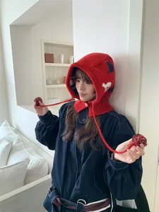 Fashionable red knit balaclava with cat pattern and pom-pom ties worn by a model