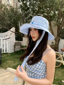 Cappello da sole a quadretti azzurro con laccio regolabile indossato da modella
