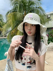 Primer plano de una mujer con un sombrero de pescador de punto blanco en una piscina de verano.