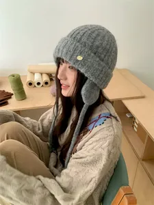 Nahaufnahme einer grauen Strickmütze mit Ohrenklappen, getragen von einem Model