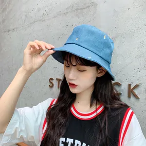 Primer plano de un gorro de pescador de mezclilla azul con bordado de letras amarillas.