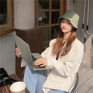 Detailed lifestyle view of a woman wearing a green pleated bucket hat at an outdoor cafe