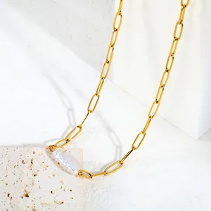 Vue détaillée d'un collier chaîne trombone en or avec un pendentif en perle baroque naturelle.