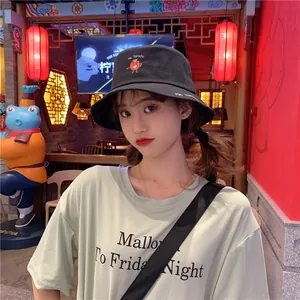 Close-up of a cute black bucket hat featuring a small tomato embroidery on a model
