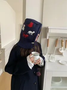 Side view of a woman wearing a navy blue knitted balaclava with cute cartoon cat patterns