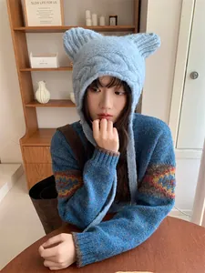 Girl wearing a light blue knitted cat ear hat with ear protection in a cozy room decor