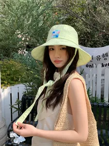 Elegante cappello a secchiello verde lime con lacci indossato da una modella in un giardino