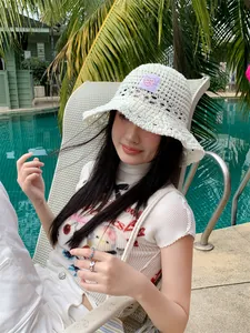 Elegante sombrero de pescador de ganchillo blanco usado por modelo junto a la piscina, verano.