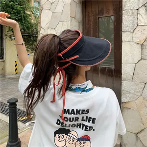 Vue arrière d'une femme portant une visière en lin noir et un t-shirt blanc à motifs.