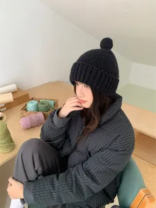 Modische schwarze Strickmütze für Damen mit niedlichem Bommel-Detail für warme Wintertage.