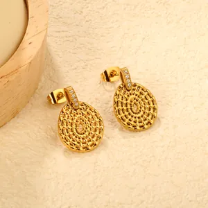 Macro detail of golden stainless steel earrings with irregular round textured dangle and crystals.