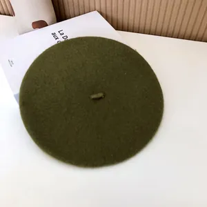 Close-up detail of an olive green wool beret hat showing soft textured fabric finish