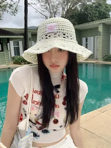 Sombrero de pescador de punto calado blanco para mujer en un entorno veraniego de piscina.