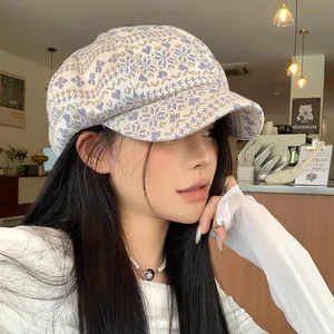 Stylish blue and beige patterned knit newsboy cap for women in a cozy cafe setting