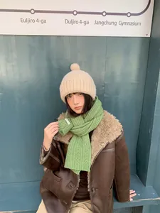 Nahaufnahme einer stylischen beigen Strickmütze mit Bommel, getragen von einem Modell