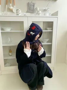 Detail view of navy blue cartoon balaclava with cat patterns in a cozy home setting