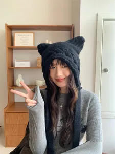 Detail view of a woman wearing a black cable-knit cat ear hat for stylish winter warmth