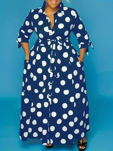 Élégante robe longue à pois bleu marine et blanc avec manches longues et ceinture.