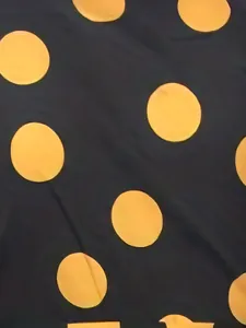 Gros plan détaillé du motif à pois jaunes sur le tissu noir d'une robe longue de mode.
