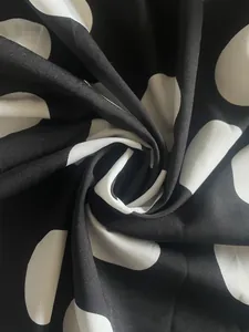 Gros plan sur un tissu imprimé à pois noirs et blancs montrant texture et motif
