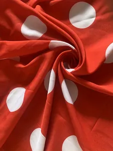 Gros plan sur un tissu rouge vif à gros pois blancs pour robes élégantes
