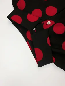 Vue macro de l'imprimé à pois rouges sur tissu noir avec détail du col à bouton blanc