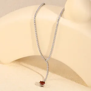 Detailopname van een elegante zilverkleurige tennisketting met een robijnrode hanger.