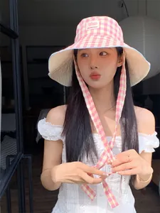 Stylish pink and yellow checkered wide-brim bucket hat with ties shown on model