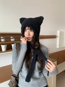 Close-up detail of a cute black knitted cat ear hat worn by a model in a cozy indoor setting.
