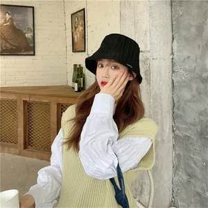 Close-up view of a black pleated sun protection bucket hat for women in a stylish cafe