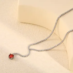 Détail d'un collier tennis en argent avec une pierre précieuse rouge ronde brillante.