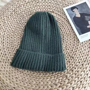 Detailed macro shot showing the ribbed texture of a dark green winter knit beanie hat