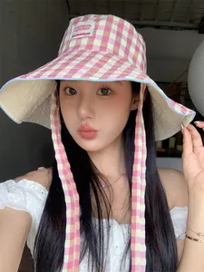 Close-up of elegant pink checkered bucket hat worn by a model with wide brim for sun protection