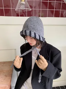Detailansicht einer grauen Damen-Strickmütze Balaclava mit schwarzen Streifen und Bändern