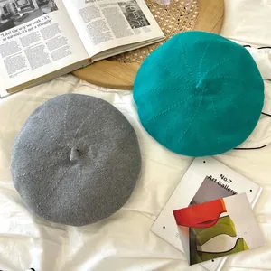 Close-up detail view of retro breathable knitted beret hats in grey and teal green colors