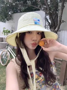 Modella asiatica che indossa un cappello da sole a scacchi giallo chiaro con lacci.