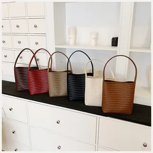 Detalle de bolsos cubo tejidos en seis colores para un estilo veraniego minimalista.