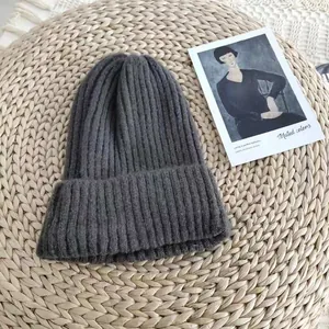 Detailed close-up showing the soft rib-knit texture of a deep grey winter beanie hat